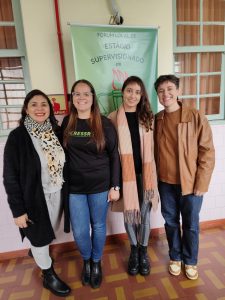4 mulheres, brancas, posam atrás de um banner escrito estágio supervisionado
