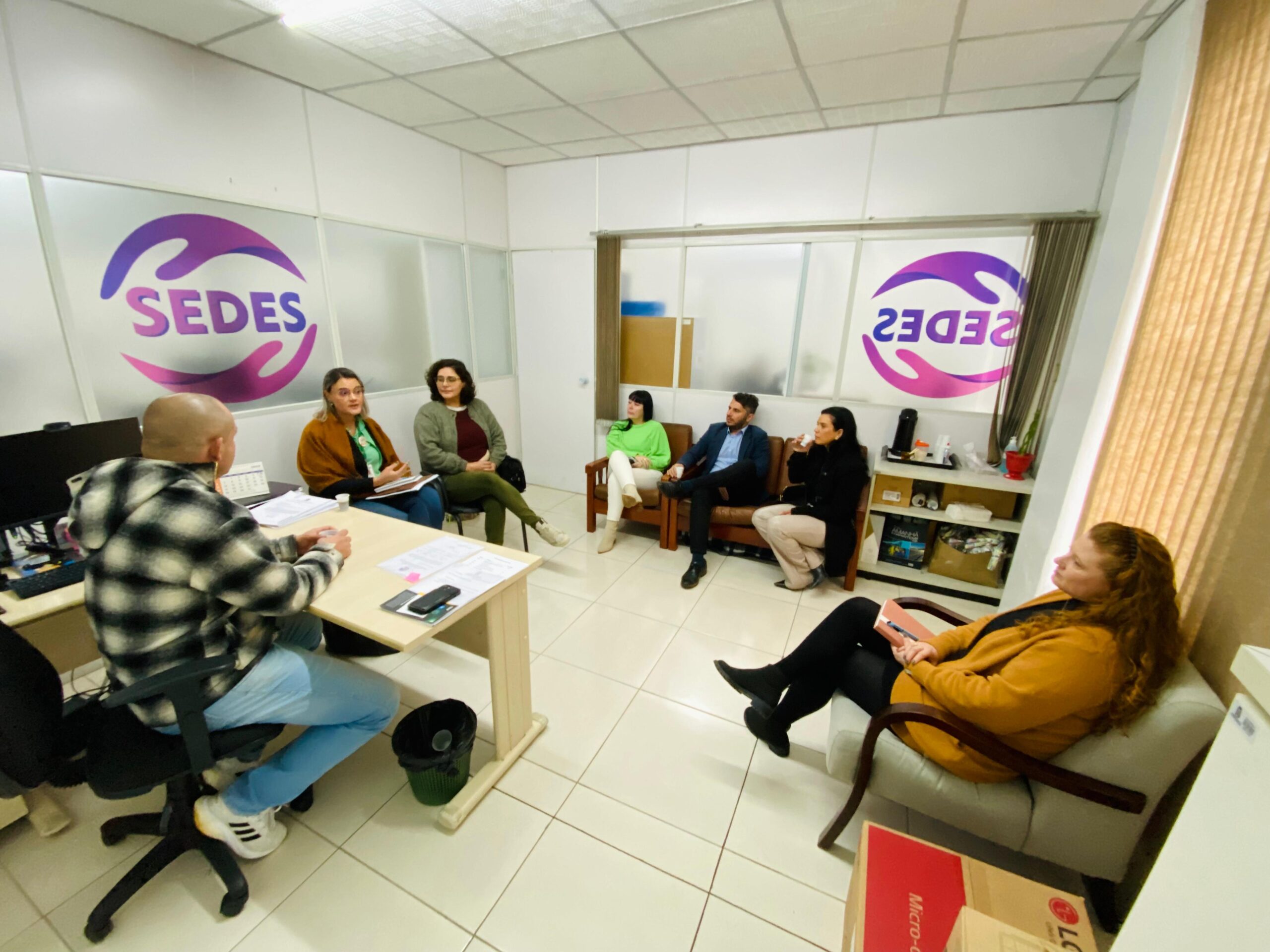 fotografia em sala de reunião com cinco mulheres e dois homens.