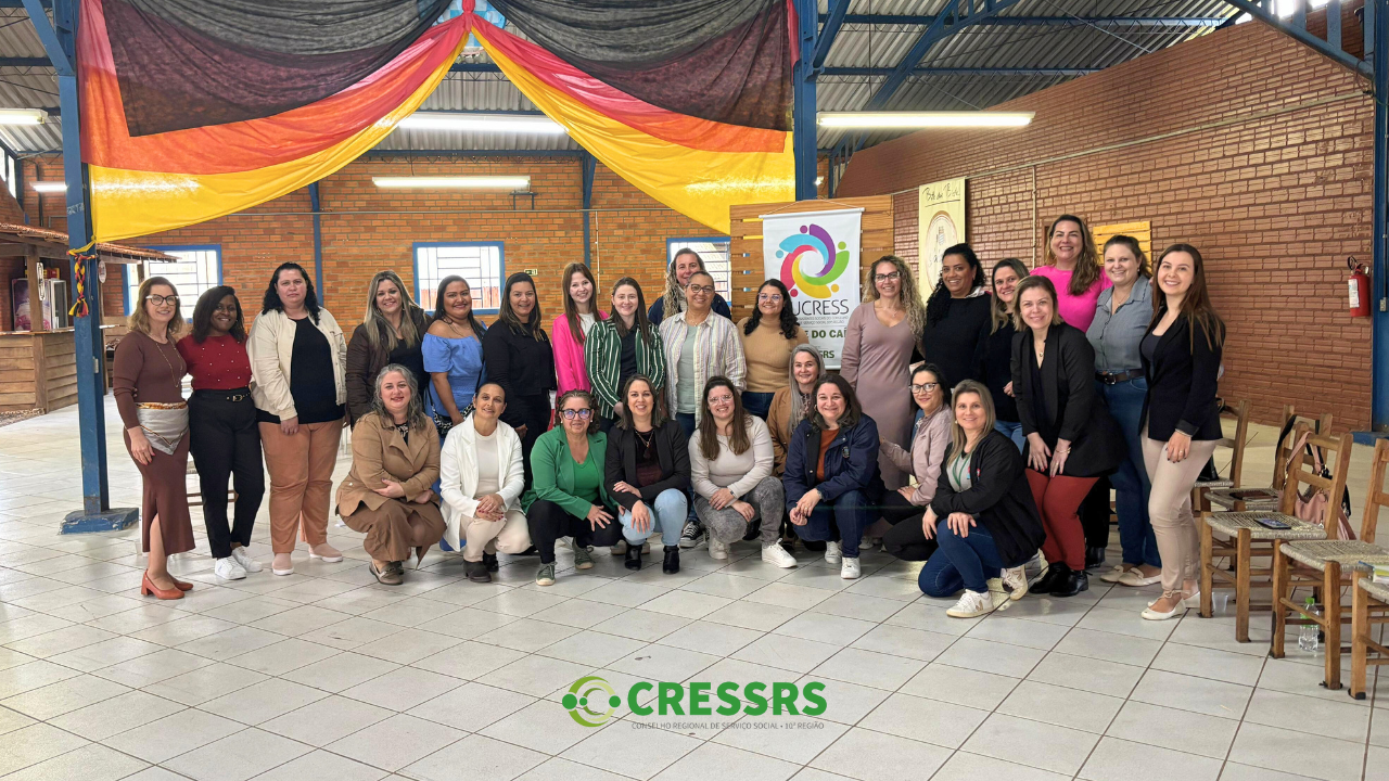 Fotografia com 27 assistentes sociais, reunidas em uma salão no encontro do NUCRESS Vale do Caí.