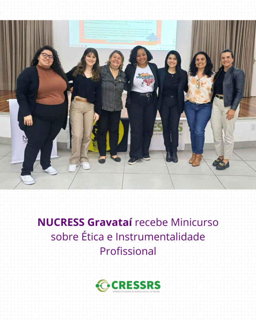 Fotografia com sete mulheres, uma negra, que veste uma camiseta com a campanha assistentes sociais do Brasil. Elas estão em um auditório.