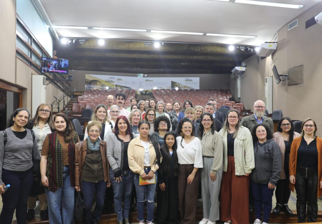 34 pessoas, de pé, no auditório da Câmara de Vereadores de Caxias do Sul. 